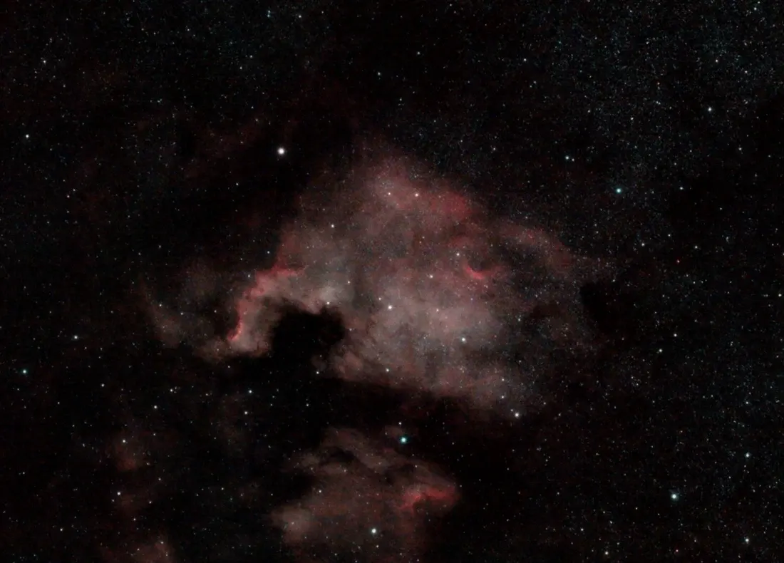 Red clouds of the North America Nebula surrounded by a dense field of stars